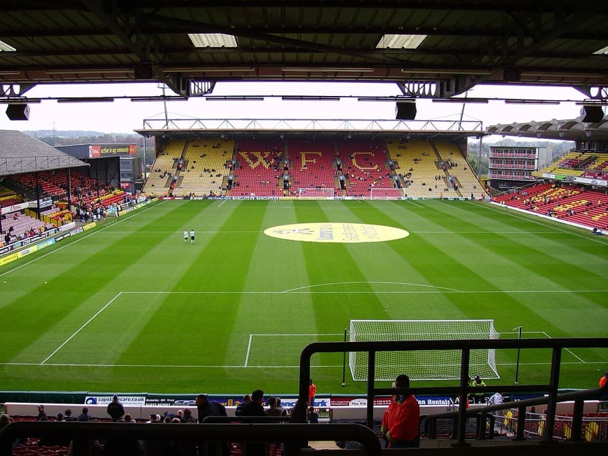 Vicarage Road em dia de jogo contra o Tottenham, em 2006, visto da arquibancada com o gramado à frente.